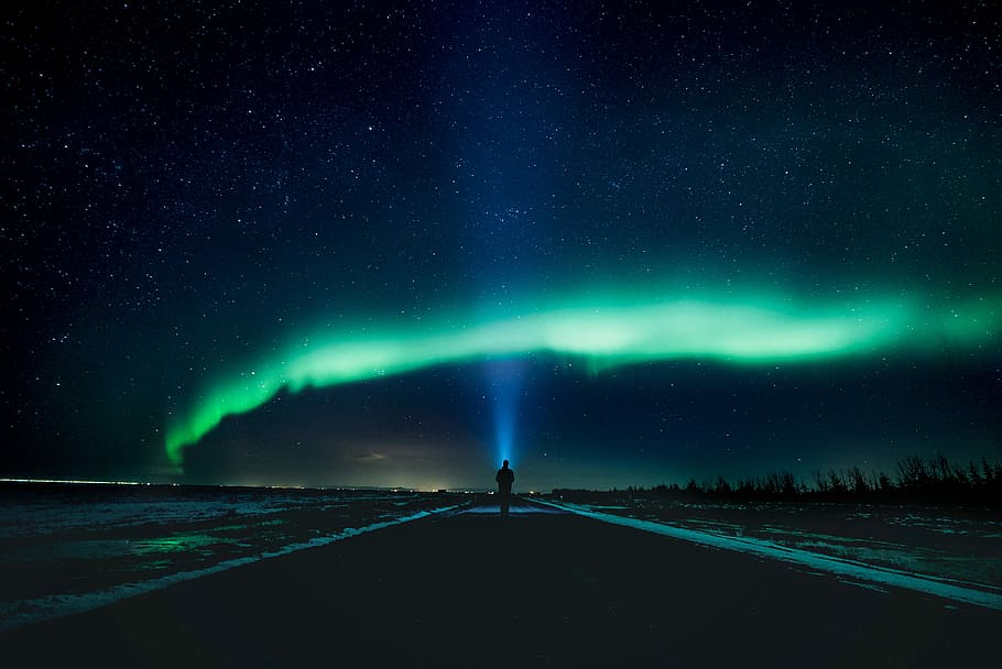 Sky Phenomenon, man standing under Northern lights during night time