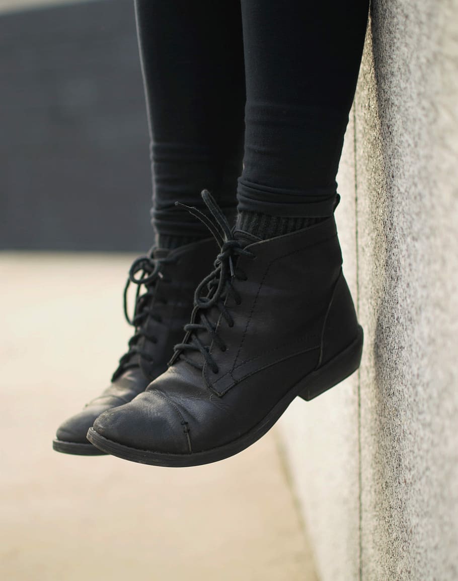 person wearing black lace-up boots, person sitting on gray concrete wall HD wallpaper