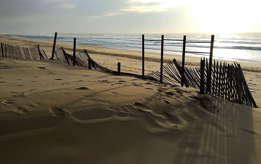 beach, sunset, evening, barrier, stakes, twilight, water, sea HD wallpaper
