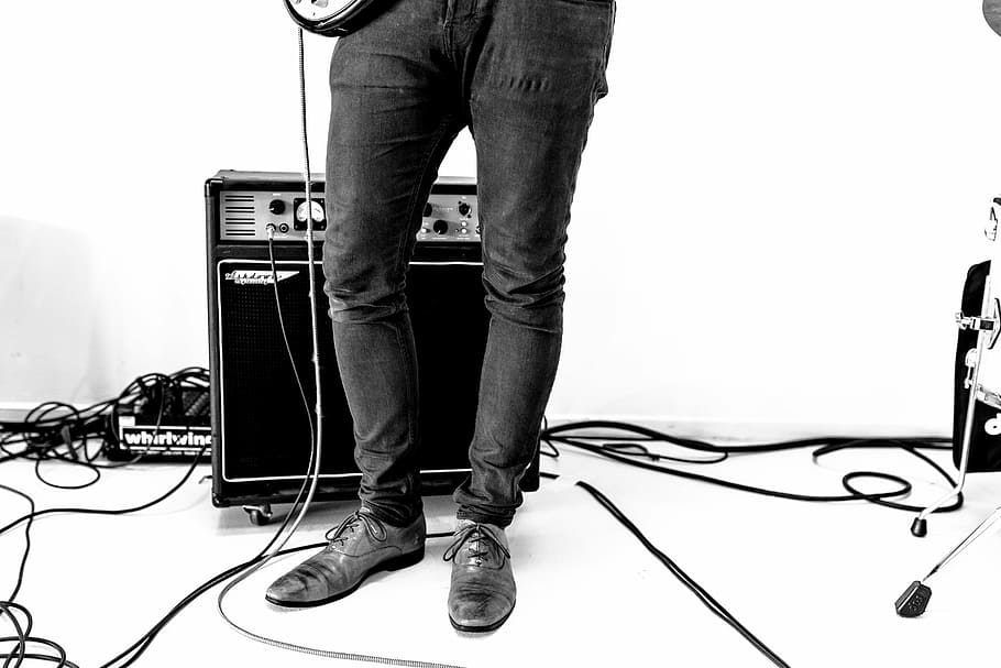 person playing guitar beside guitar amplifier, black, white, shoe