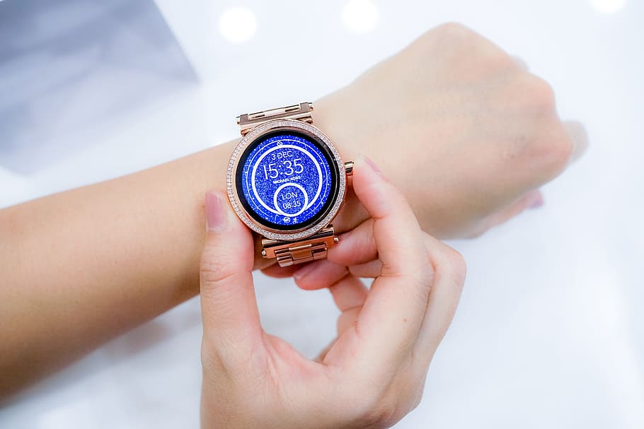 person holding gold-colored smartwatch on her left wrist, hands HD wallpaper