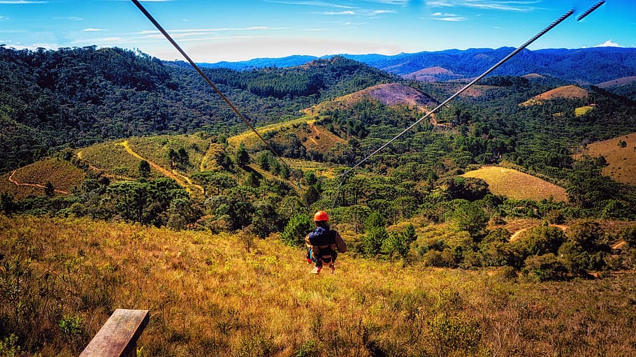 person riding on zip-line, zipline, mountain, hill, forest, adventure