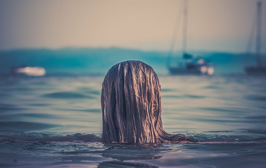 woman in body of water, blonde, haired, near, boat, white, sky