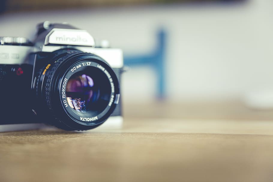 black and silver SLR camera placed on brown wooden surface, analog