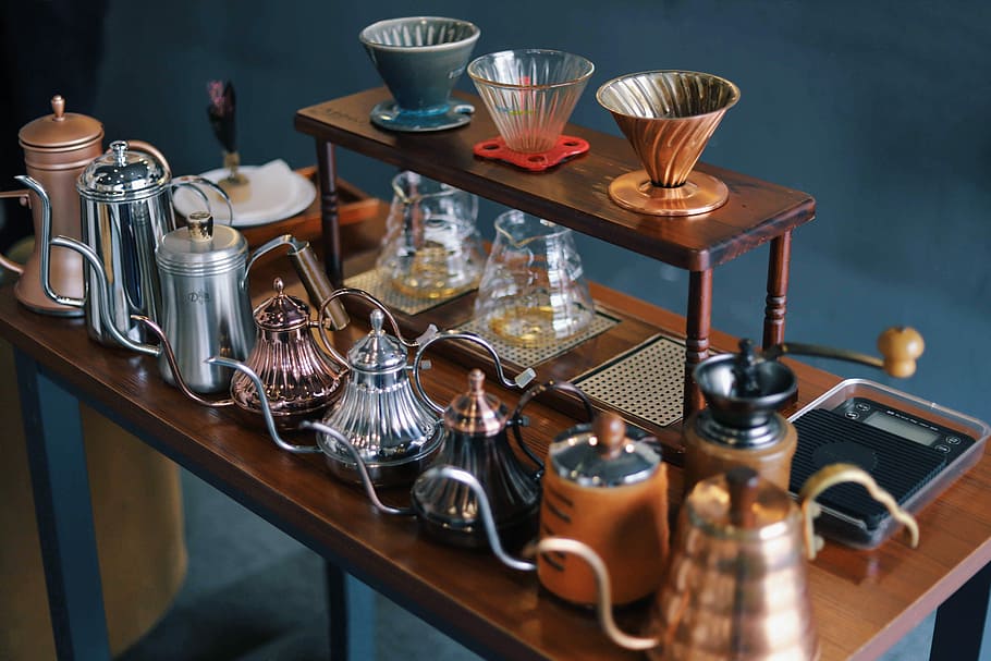 assorted-color dallah lot, assorted teapots on brown wooden console table HD wallpaper