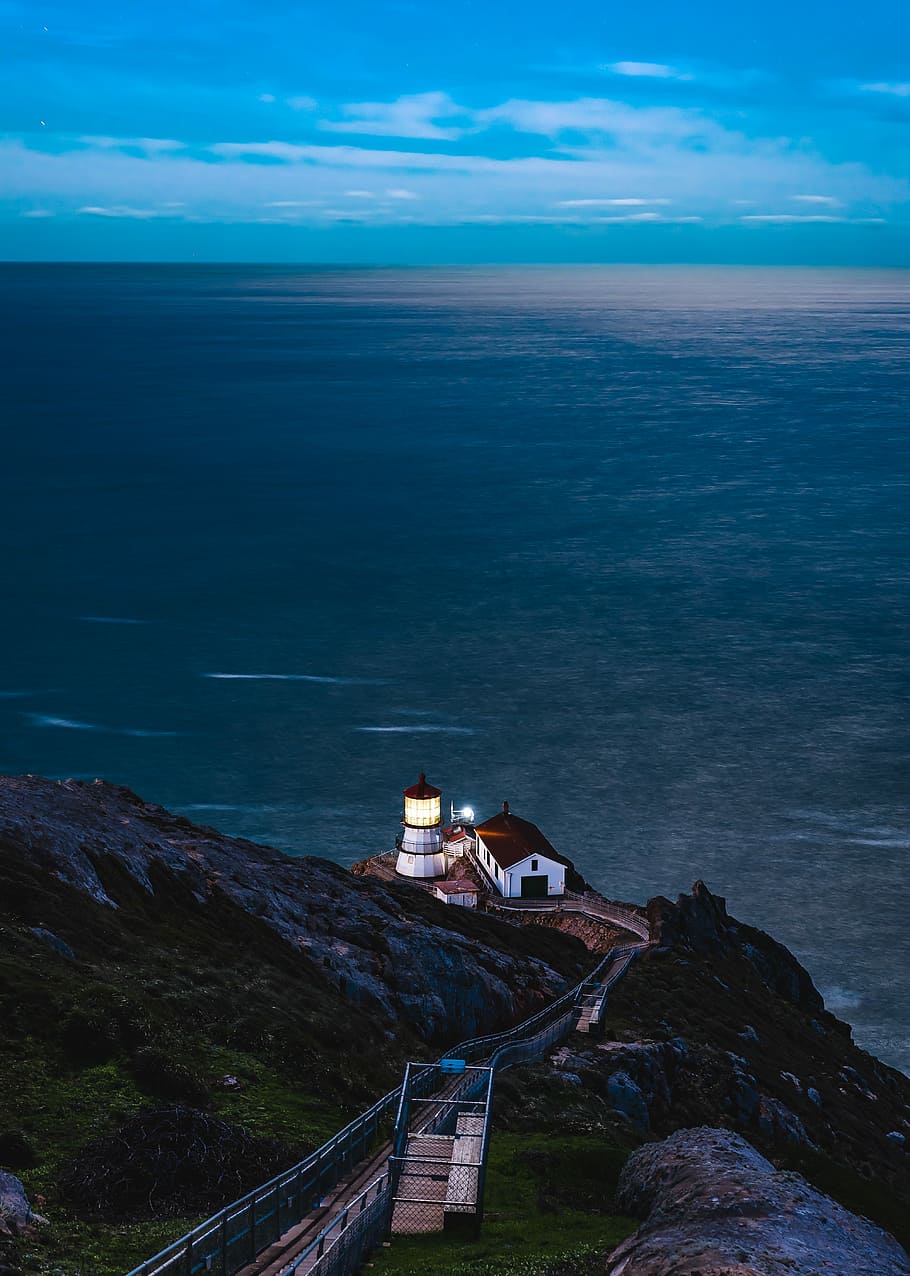 aerial view of white and tower near shore, white and red lighthouse near body of mountain HD wallpaper