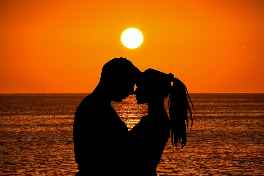 man and woman hugging by the beach with ocean on the horizon during sunset HD wallpaper