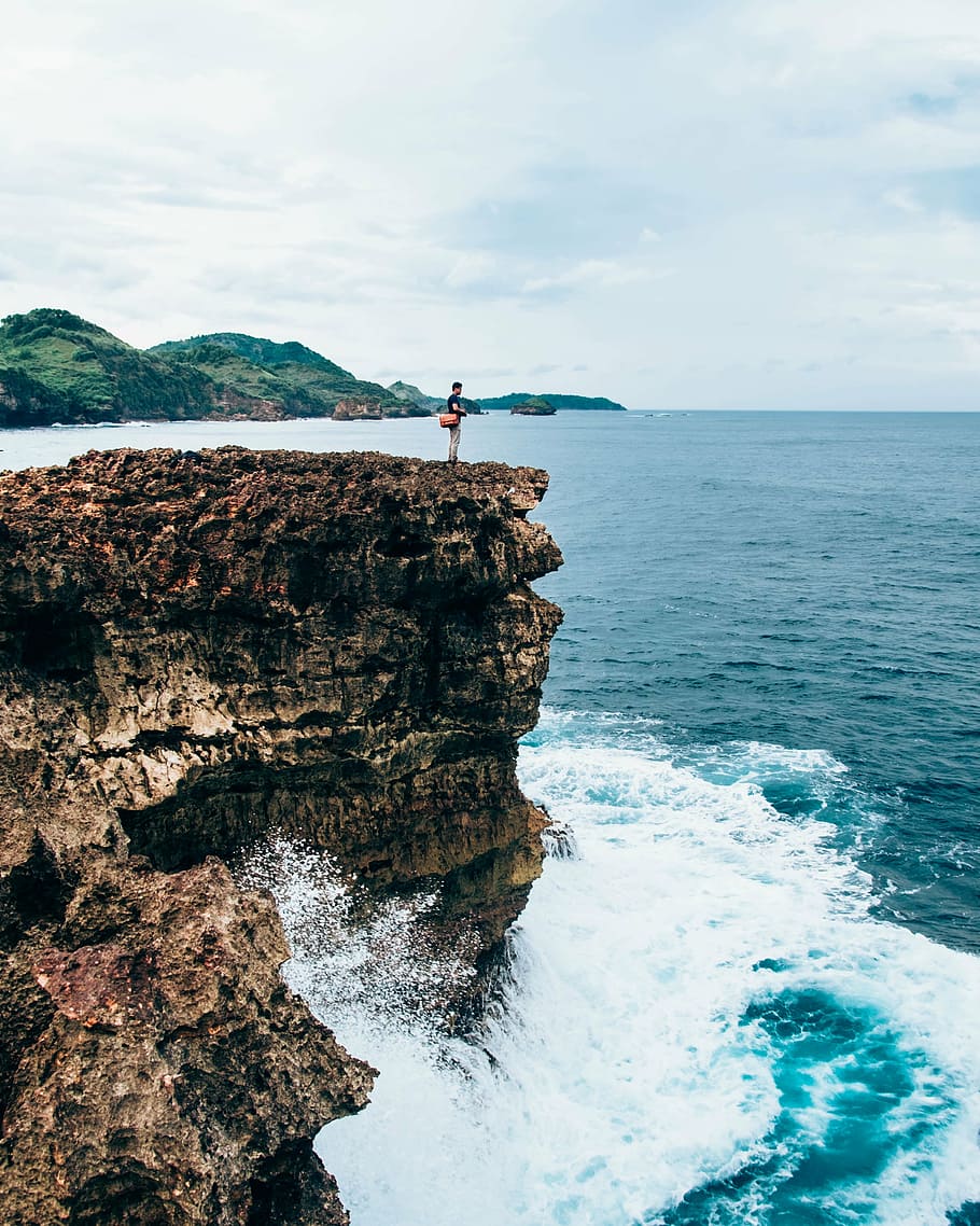 person standing on cliff near body of water, photo, man, mountains HD wallpaper
