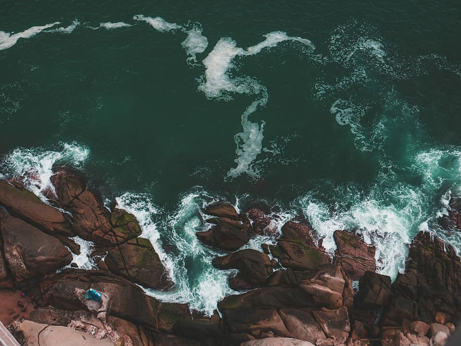 tidal waves into rock, aerial view from top of mountain cliff with teal ocean water during daytime HD wallpaper