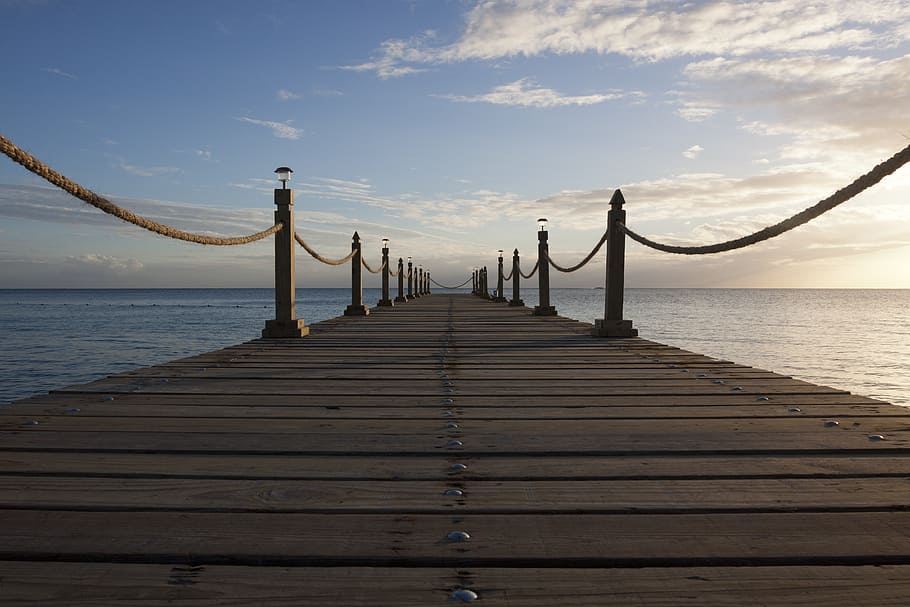 landscape photo of sea dock under stratocumulus clouds, brown wooden dock
