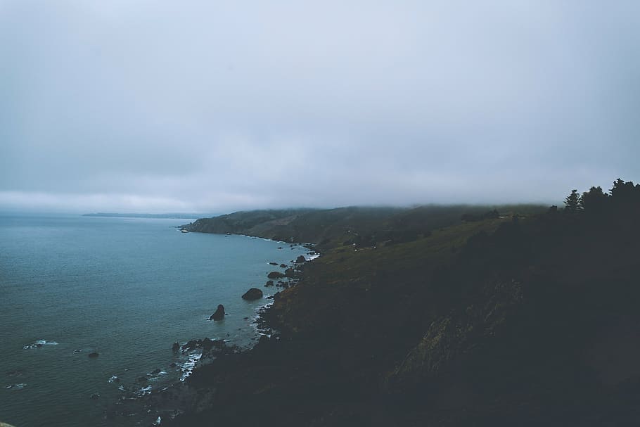 aerial photography of mountainside beside body of water during daytime HD wallpaper