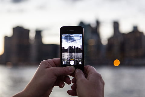A person captures the sunset over the Manhattan skyline in New York with their iPhone mobile smartphone. Image taken from DUMBO, Brooklyn HD wallpaper