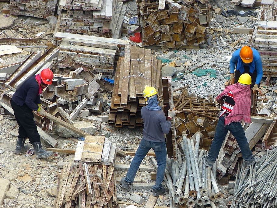 construction workers on yard carrying metal, building construction