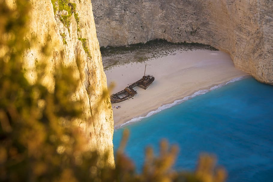 ship wreck on shore, brown boat on seashore near rock formation HD wallpaper