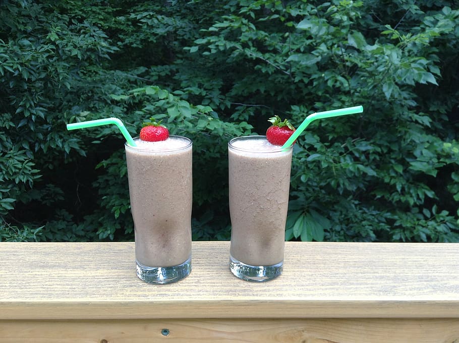 two milkshakes on brown wooden surface, chocolate, peanut, butter