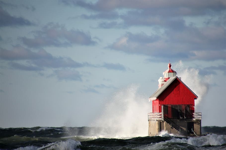 red and white lighthouse on body of water during daytime, building