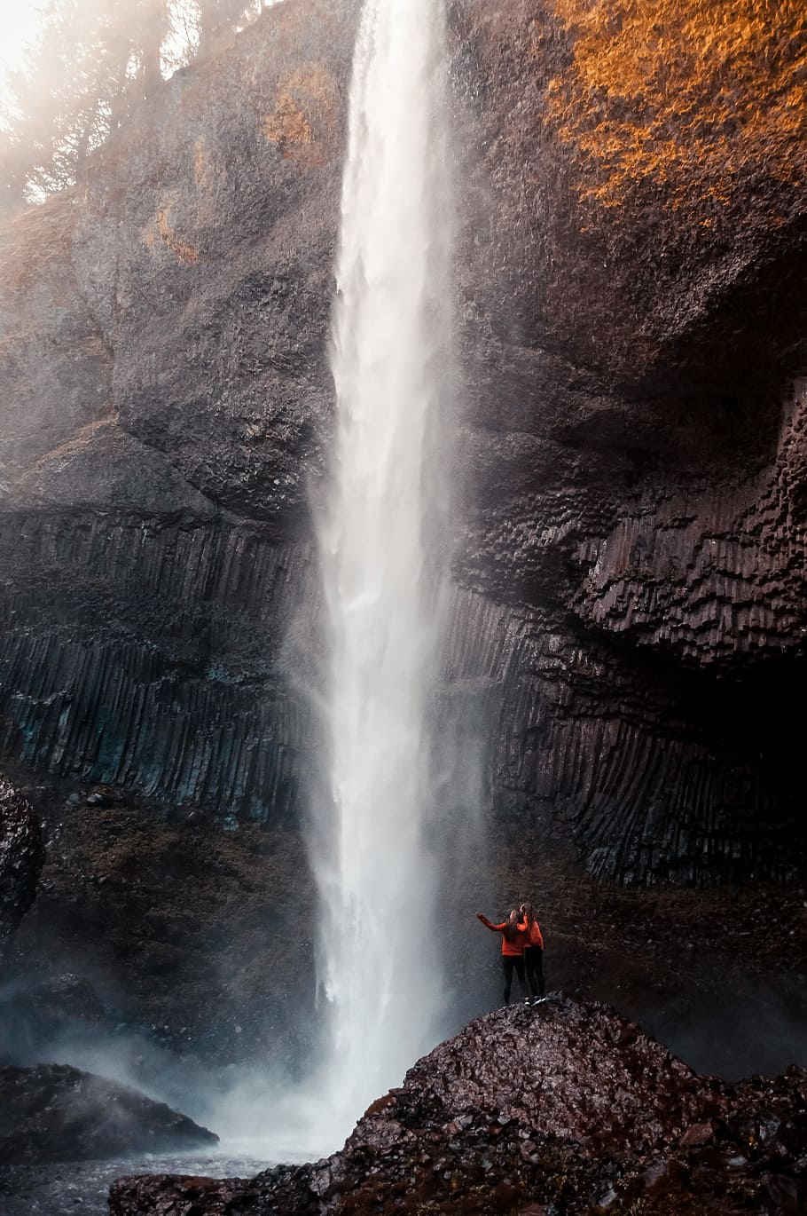 two person standing near waterfalls, two person looking on waterfalls