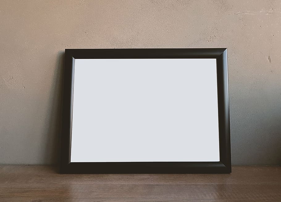 black photo frame leaning on brown wall, border, white, floor