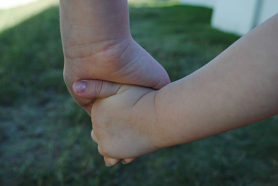 selective focus photo of two person holding each other's hand