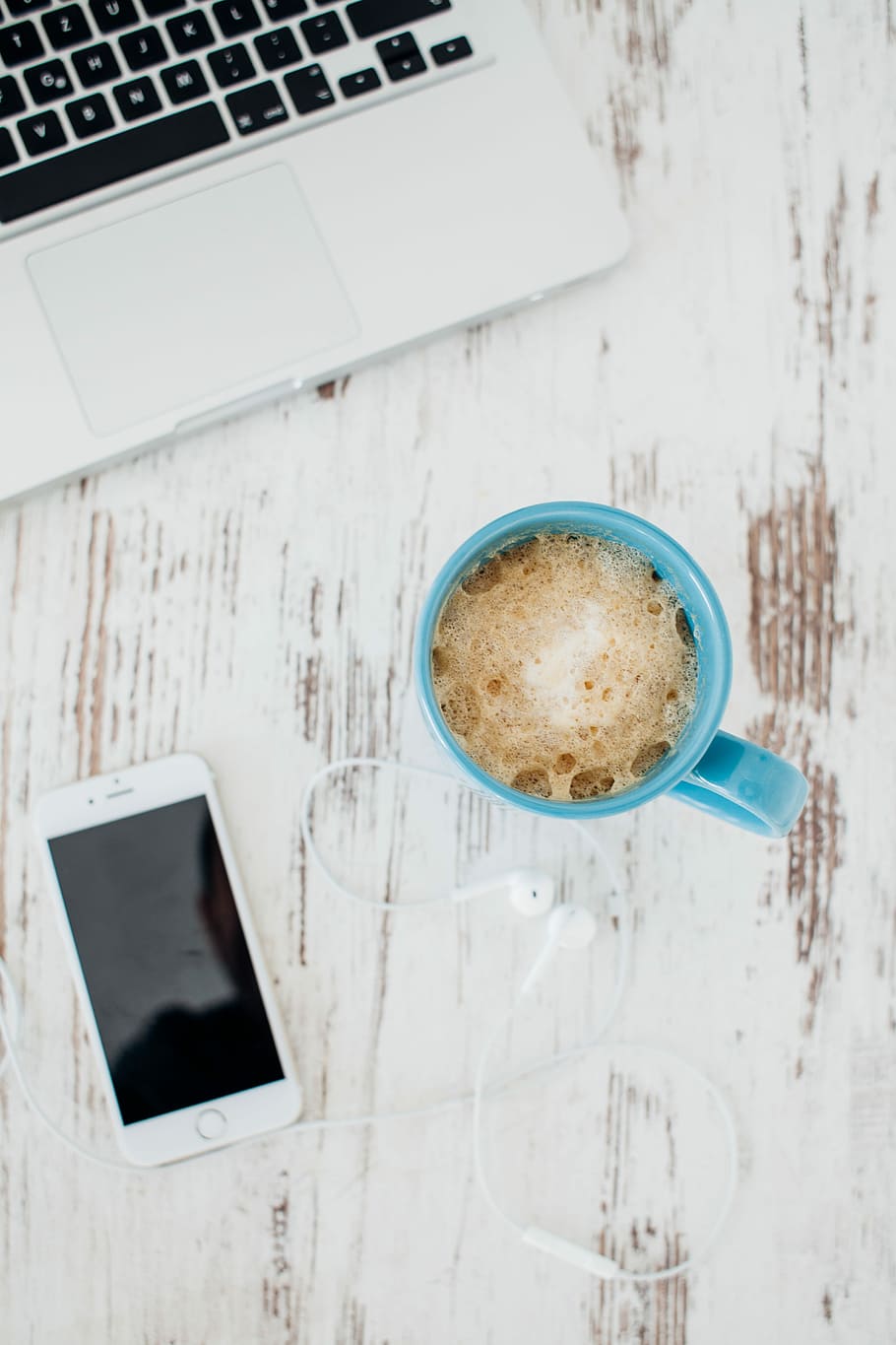 flat lay photography of coffee in blue mug near Apple EarPods and gold iPhone 6, flat-lay photography of blue mug with coffee beside iPhone and EarPods on table
