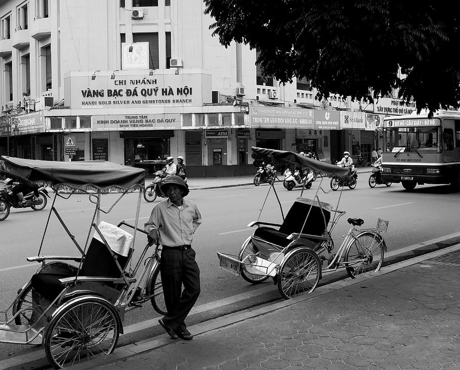 man standing on trike, vietnam, hanoi, black and white, street