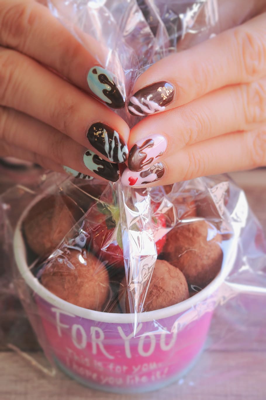 woman in blue, pink and black nail polish white holding chocolate ball plastic cover HD wallpaper