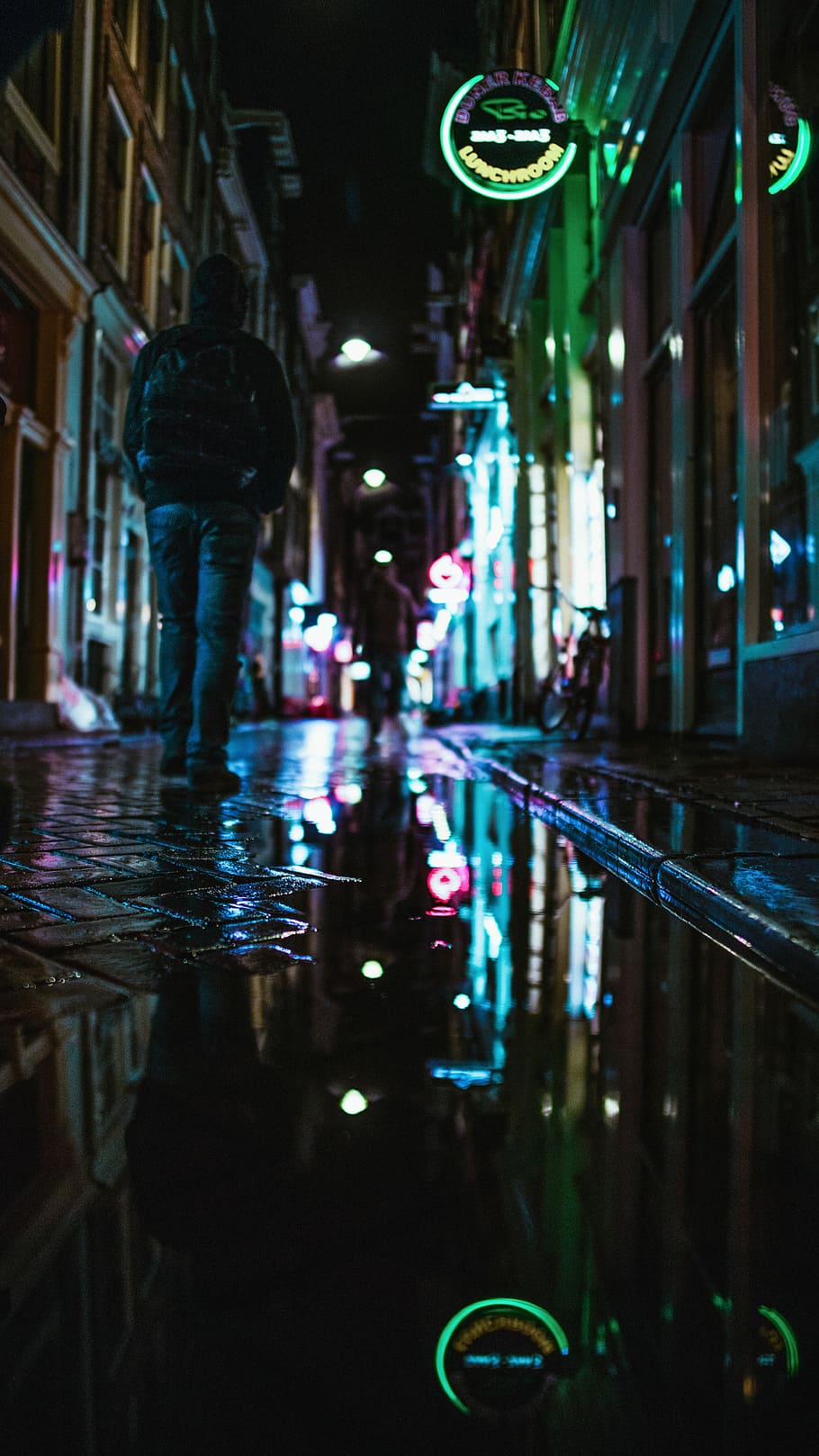 man wearing jacket walking between buildings during nighttime, person walking on hallway during nightime HD wallpaper