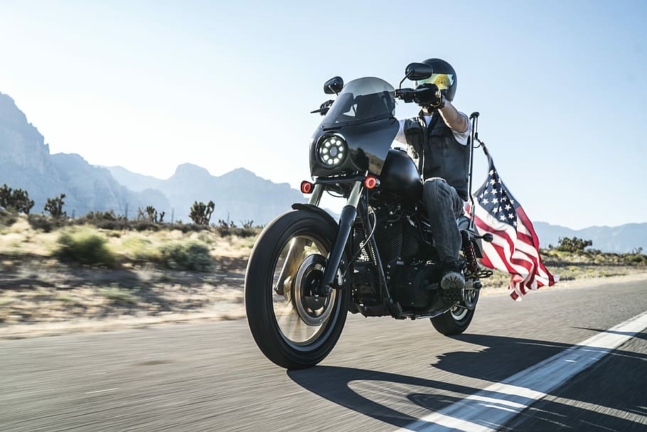 man riding motorcycle with USA flag on back, man riding black touring motorcycle in rule of thirds photography HD wallpaper