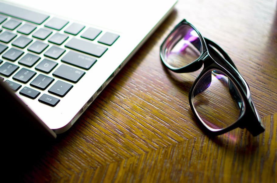 eyeglasses with black frame beside MacBook Pro, computer, still life HD wallpaper