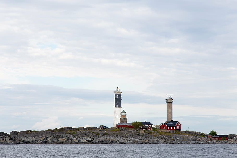 two white and brown lighthouse under white and blue cloudy skies at daytime