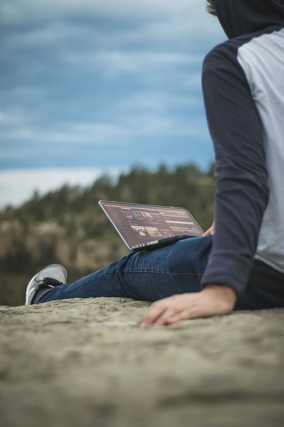 man sitting on cliff with laptop on legs, man sitting on mountain cliff under blue sky during daytime HD wallpaper
