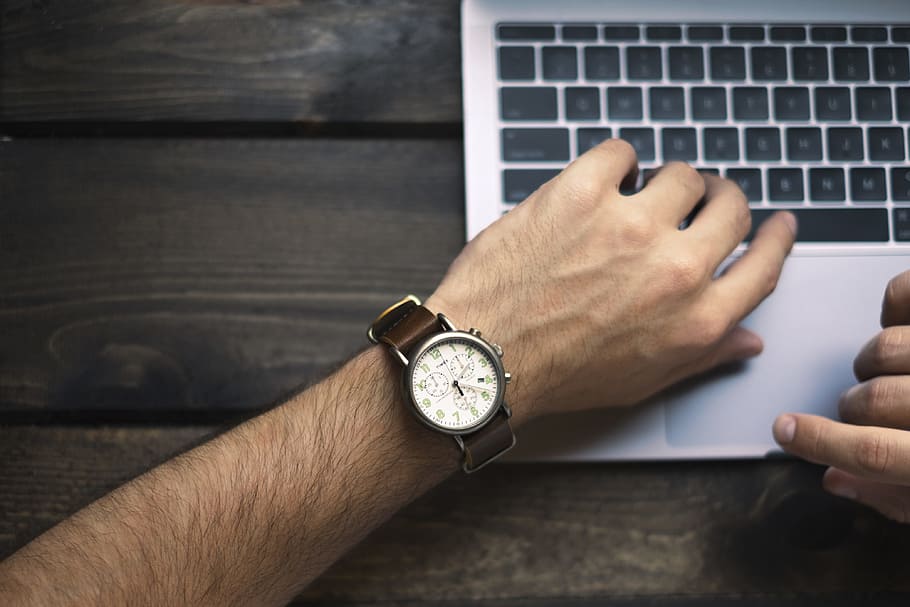 person wearing brown and white watch, man in white analog watch holding silver laptop computer