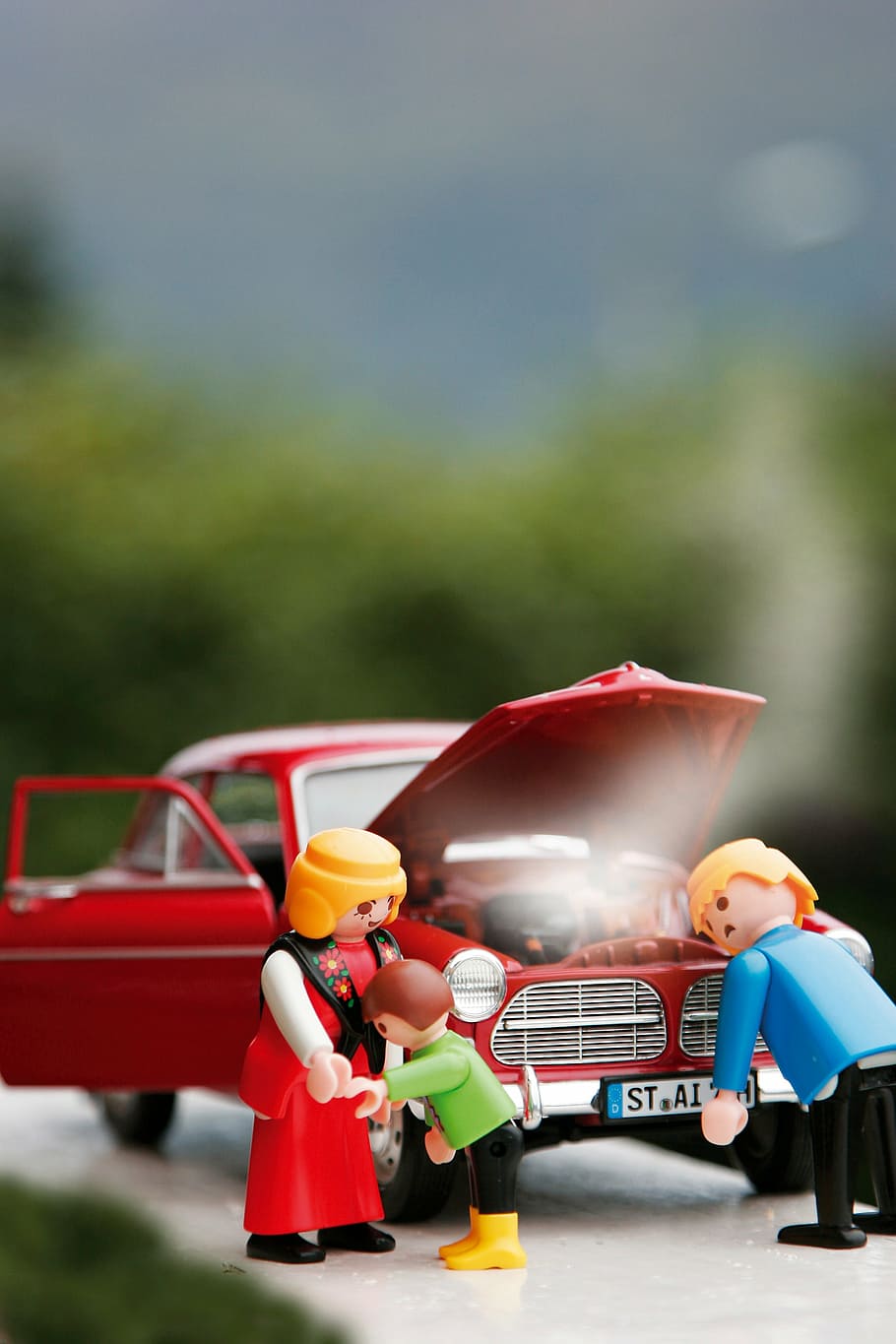selective focus photography of three minifigs beside red vehicle