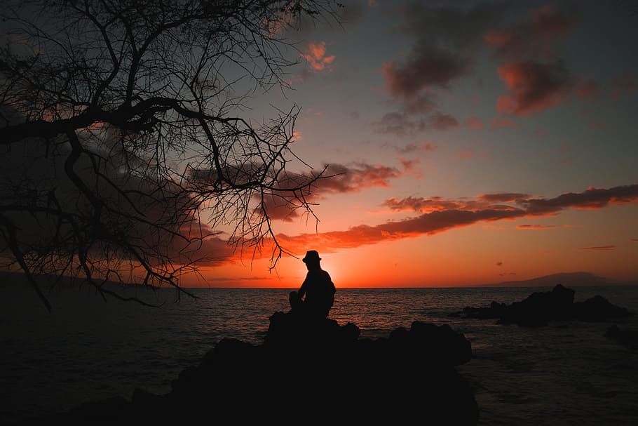 Silouhette of Person Seating on Stones Behind Body of Water, backlit HD wallpaper