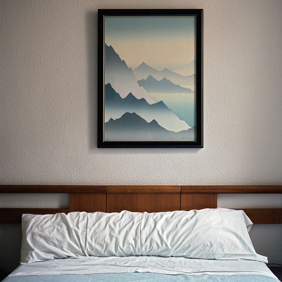 black wooden framed decor, mountains painting near white bed pillow