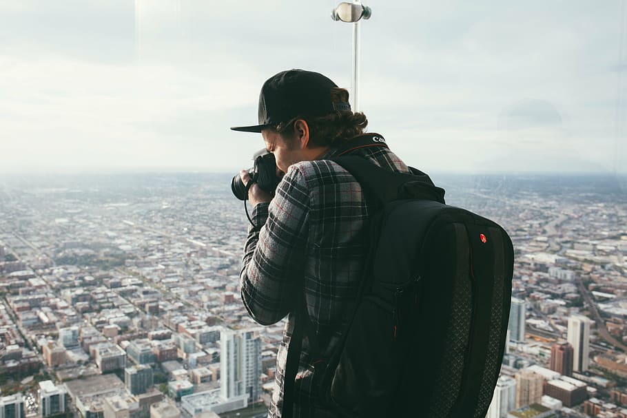 man taking photo of buildings using black DSLR camera during daytime HD wallpaper