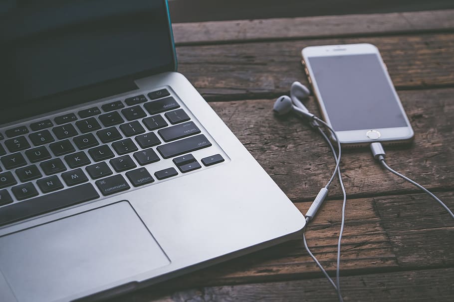 iPhone displaying black screen beside MacBook on table, computer HD wallpaper