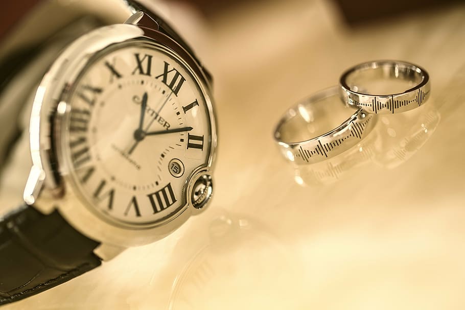 round silver-colored analog watch beside two silver-colored rings