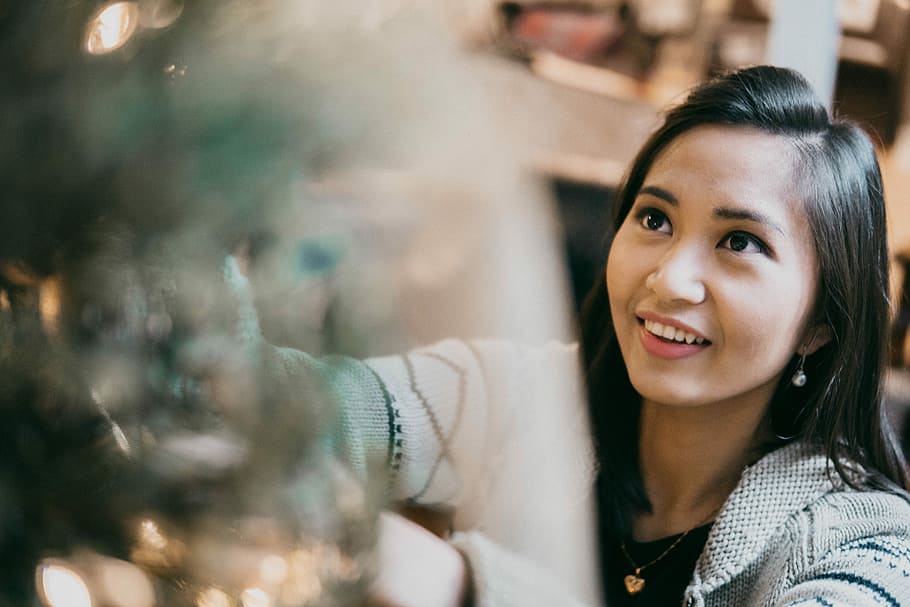 woman smiling while decorating at Christmas tree, woman wearing gray top HD wallpaper
