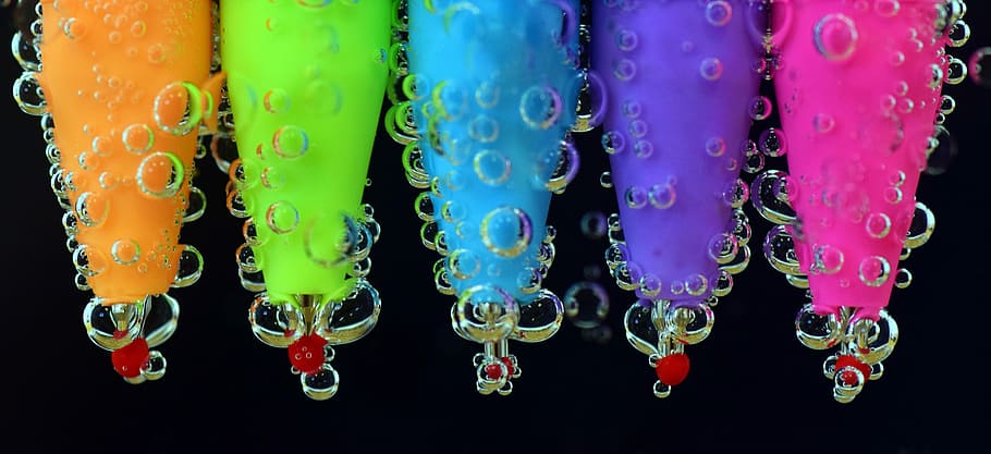 microphotography of five assorted-color pen submerge on water
