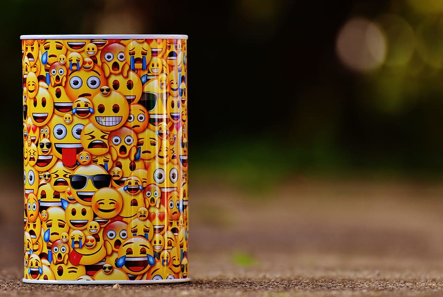 Emoji printed can on brown surface in close-up focus photography during daytime