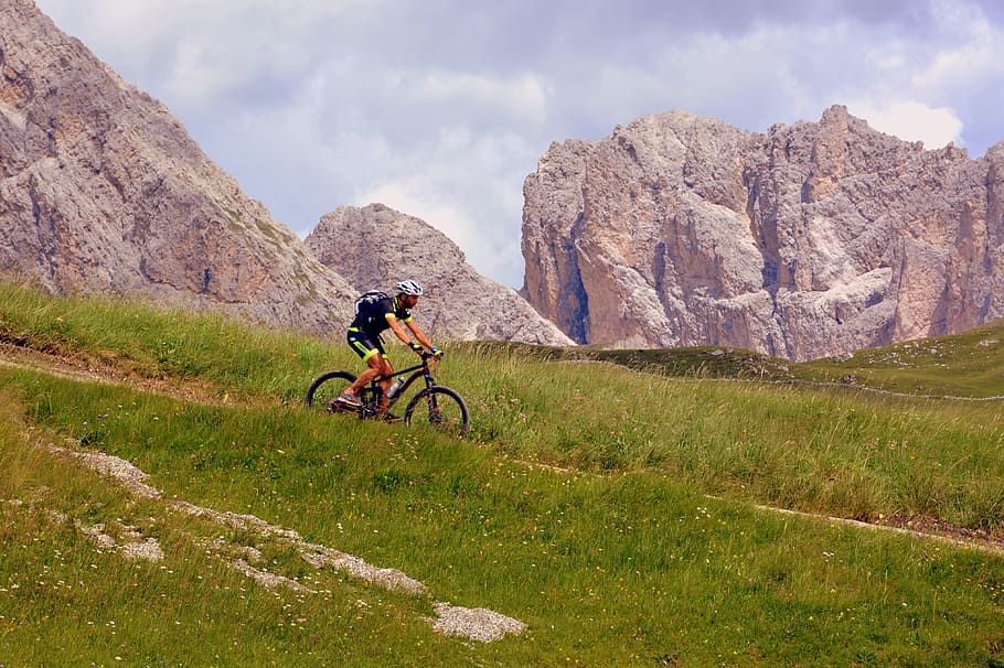 man riding bicycle along green grass field, hiking, mountain biking