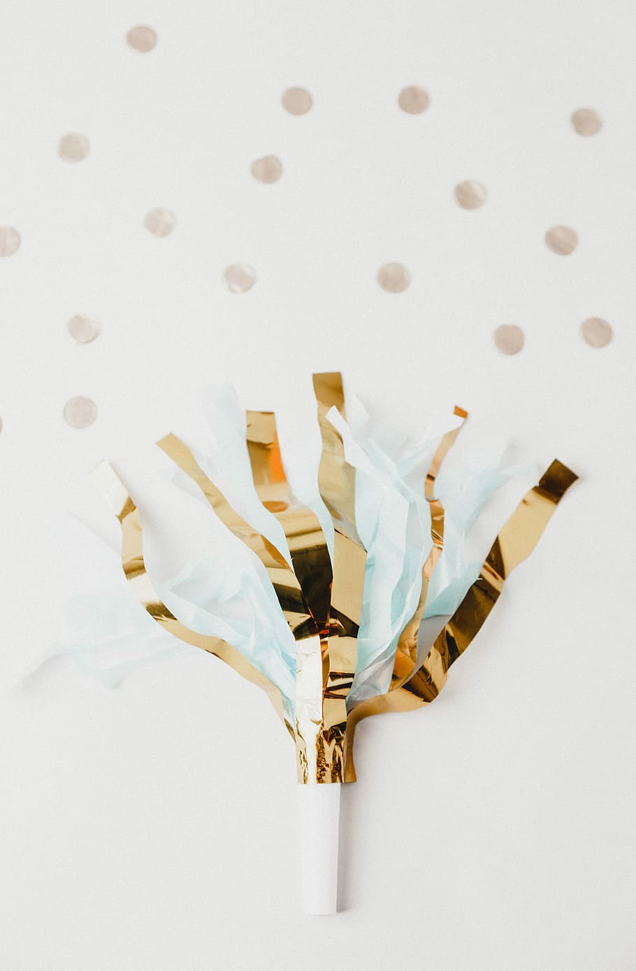 white and brown foil party decor on white panel, yellow and blue pompom