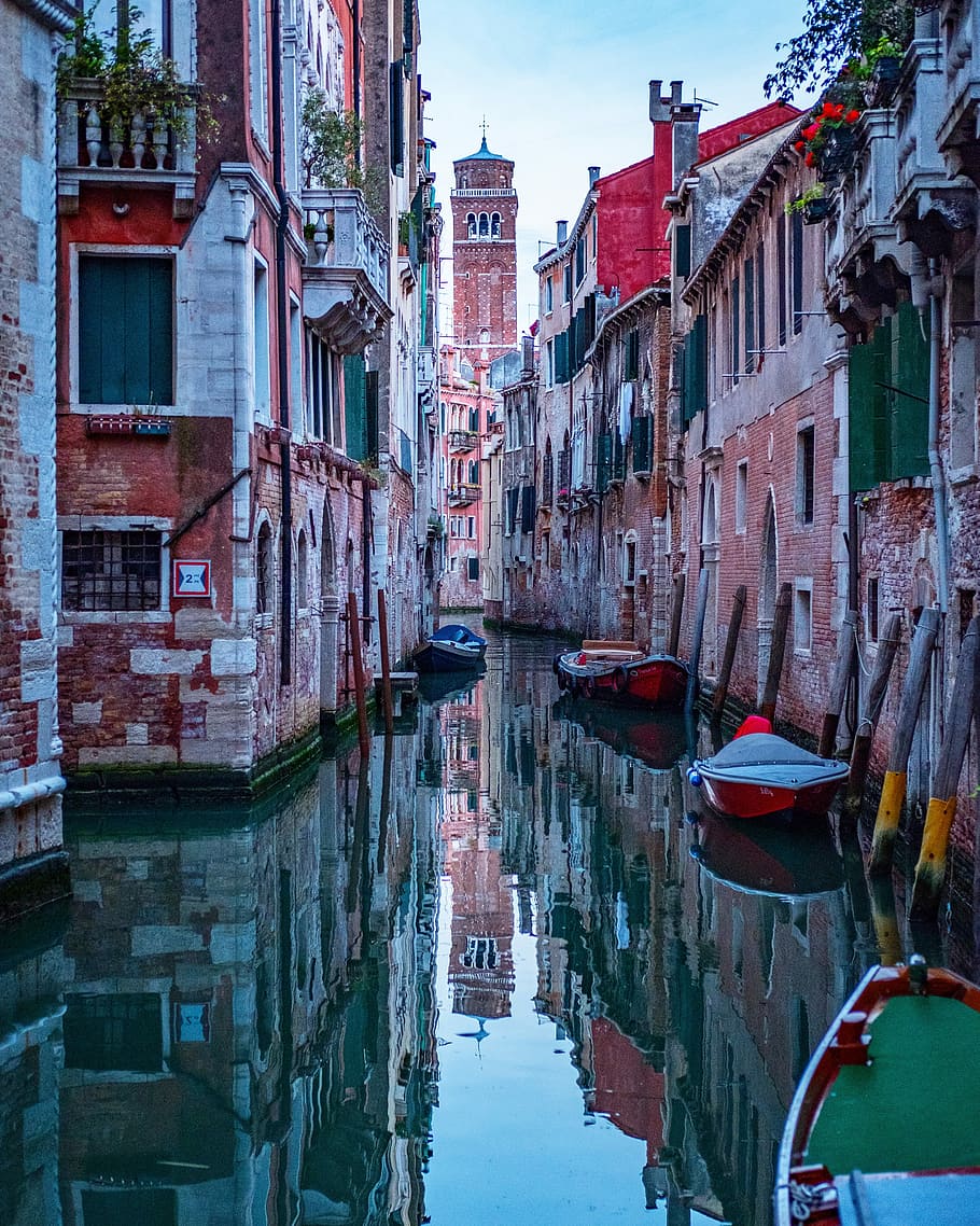 boats docked near brown buildings, two red boats on body of water HD wallpaper