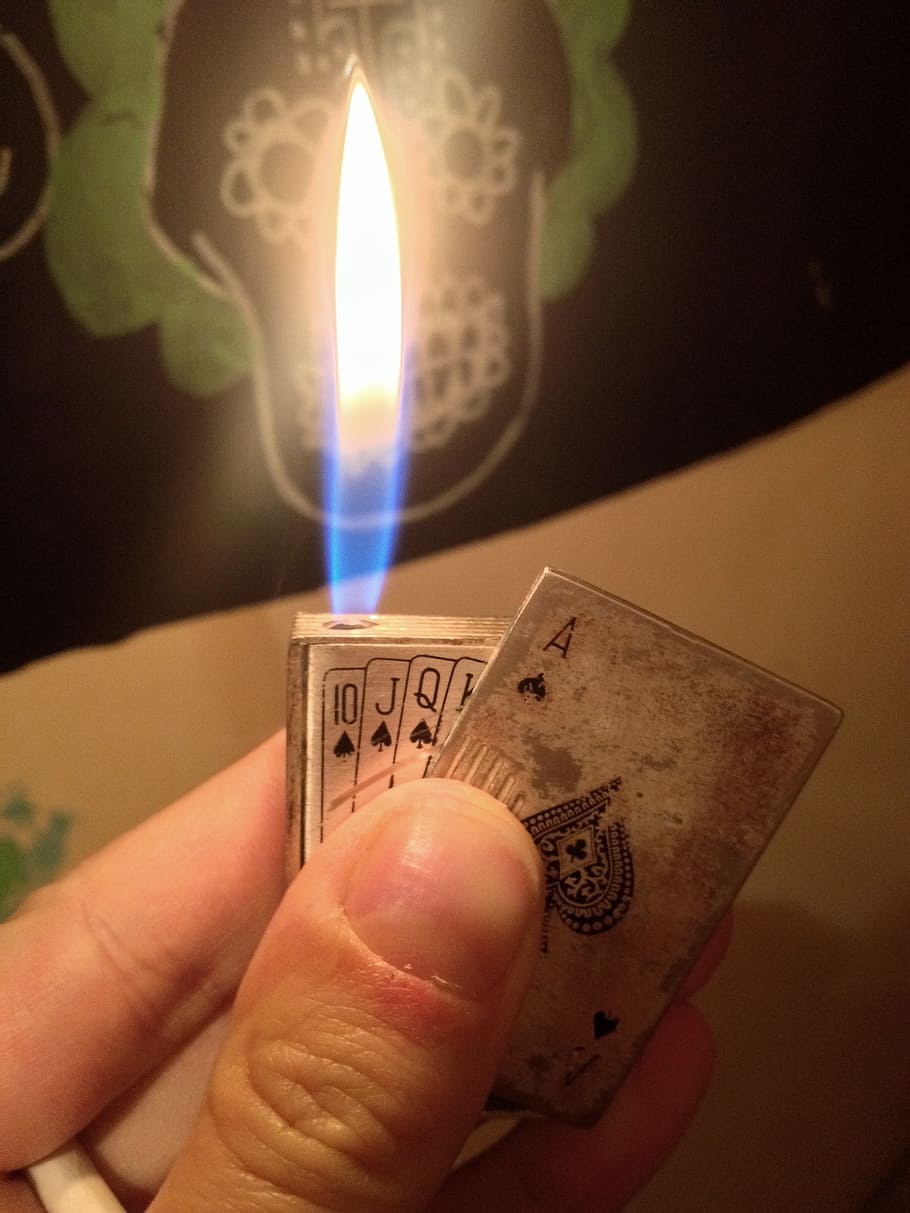 person holding playing card-themed Zippo flip lighter, poker