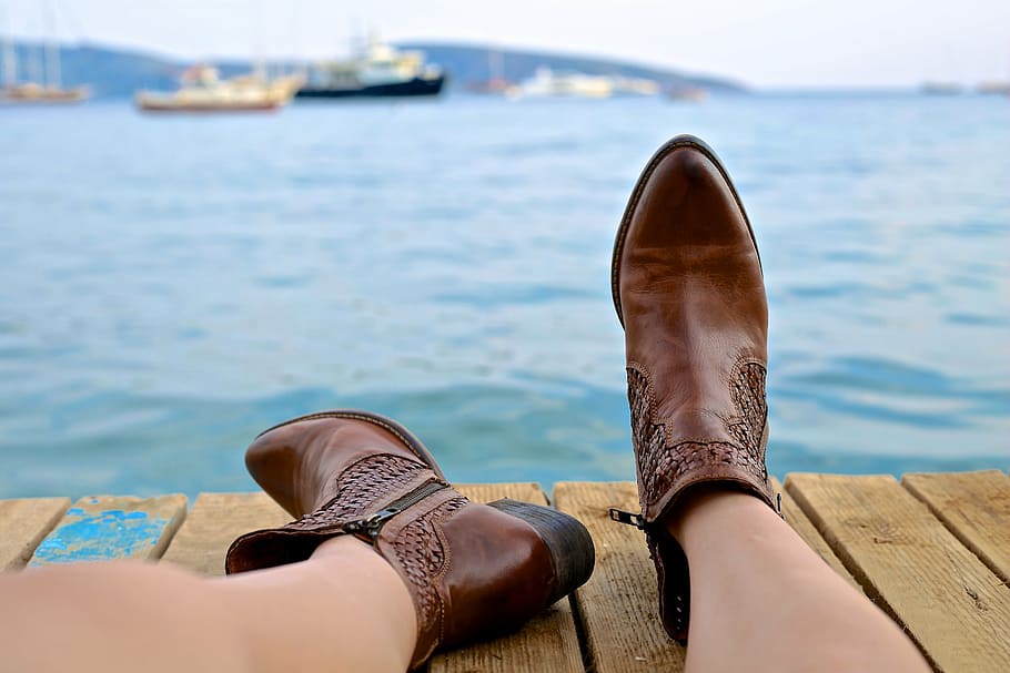 woman wearing brown leather boots near body of water and boats at daytime, HD wallpaper