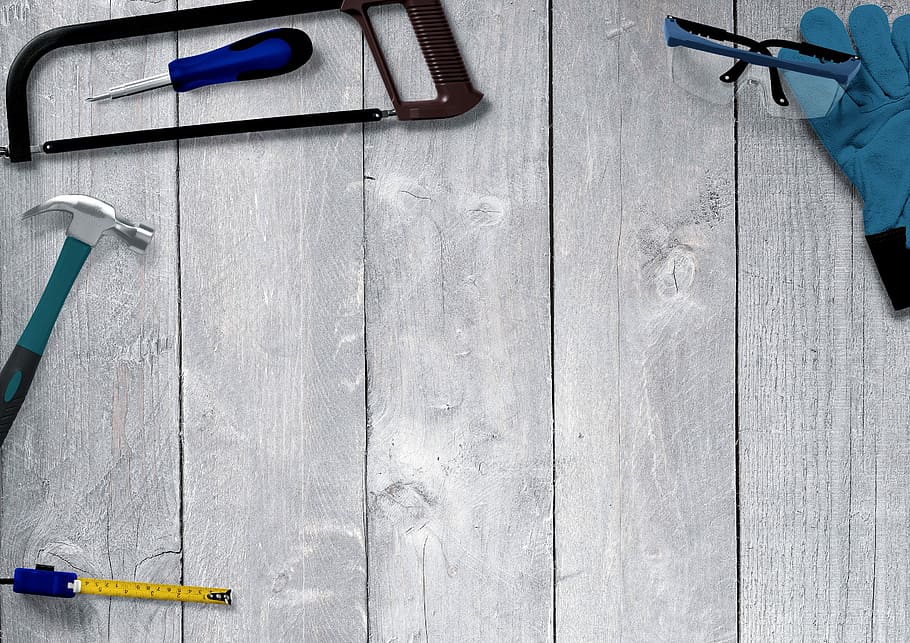 black framed safety glasses, black hacksaw, gray claw hammer, and yellow measuring tape on top of gray board HD wallpaper