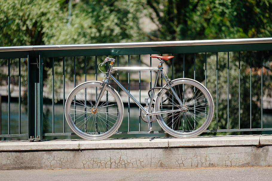 gray bicycle parked on bridge rails, gray road bike beside gray metal railing during daytime