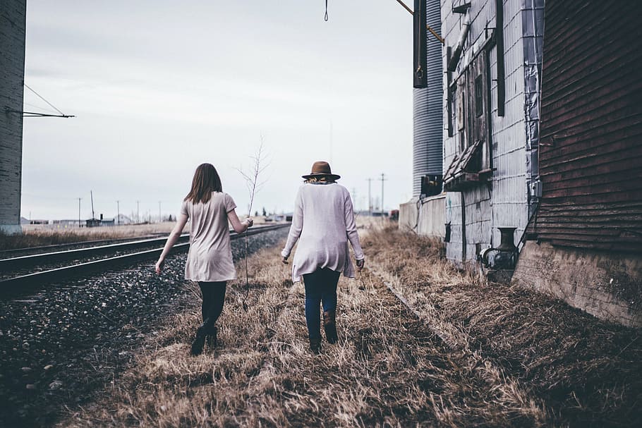 two women walking on grass field beside train rails, architecture, HD wallpaper