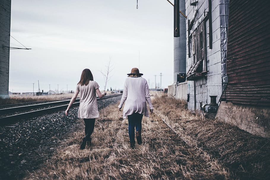 two women walking on grass field beside train rails, architecture HD wallpaper